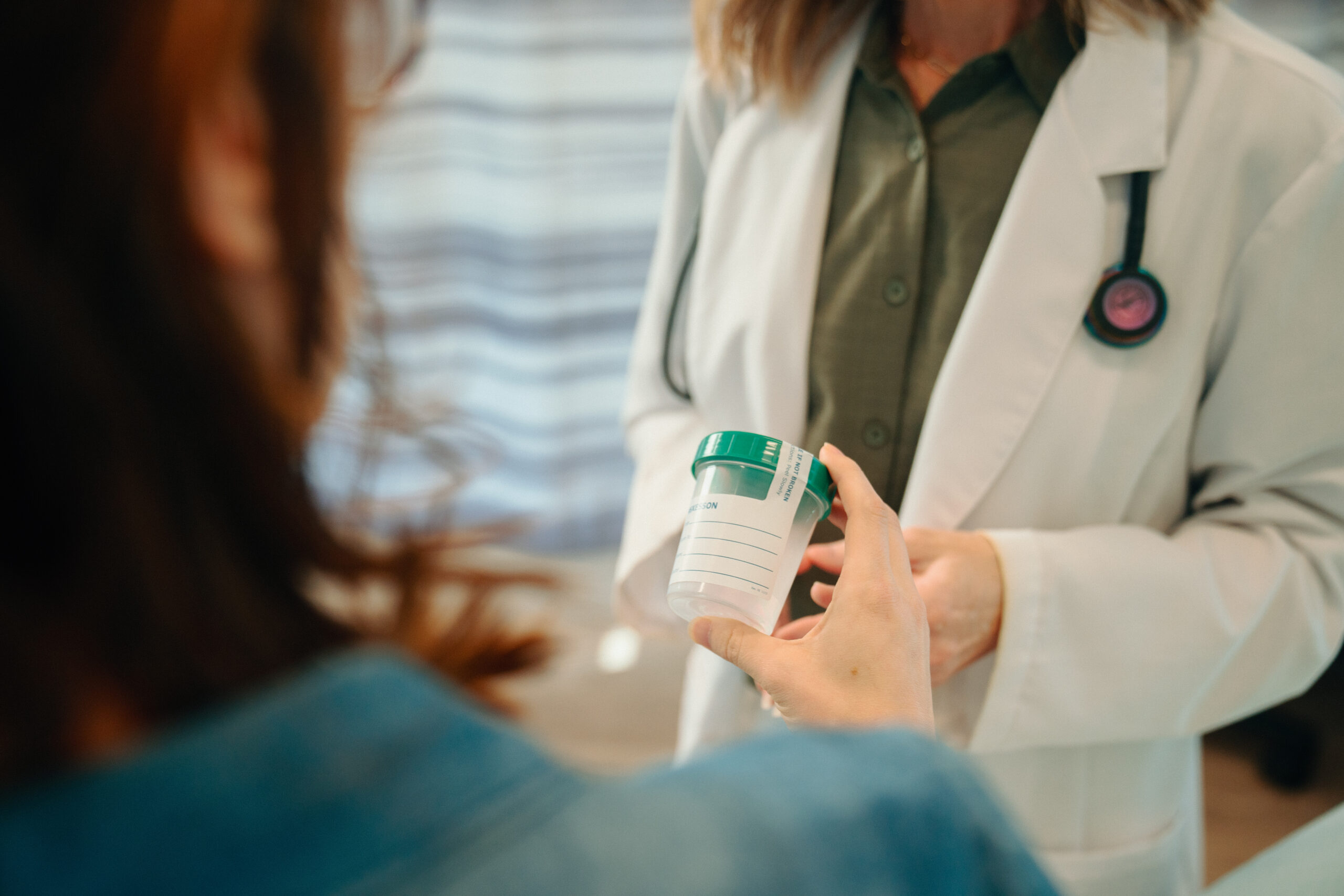 AFC provider and patient hold urine cup discuss UTIs